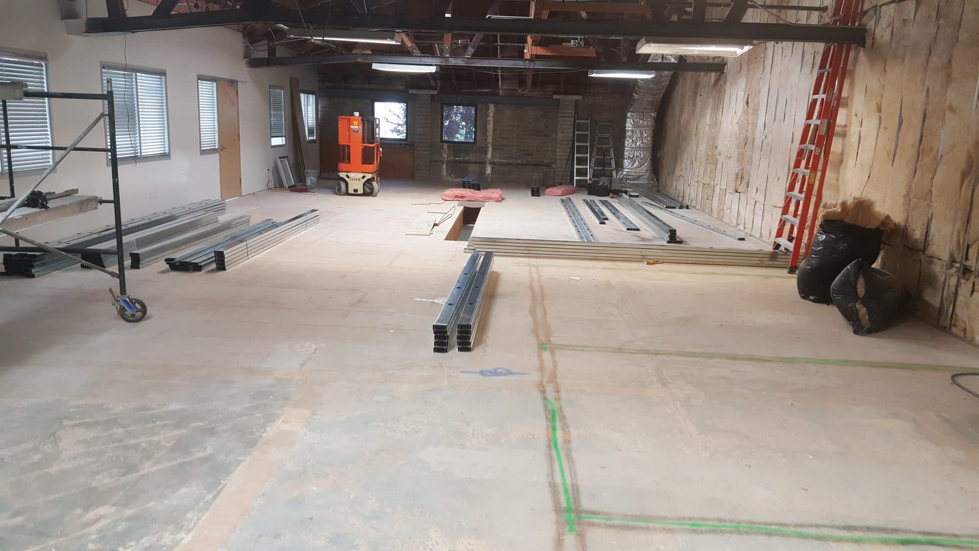 Open shell with chalk-line layout on the slab and metal studs staged for framing