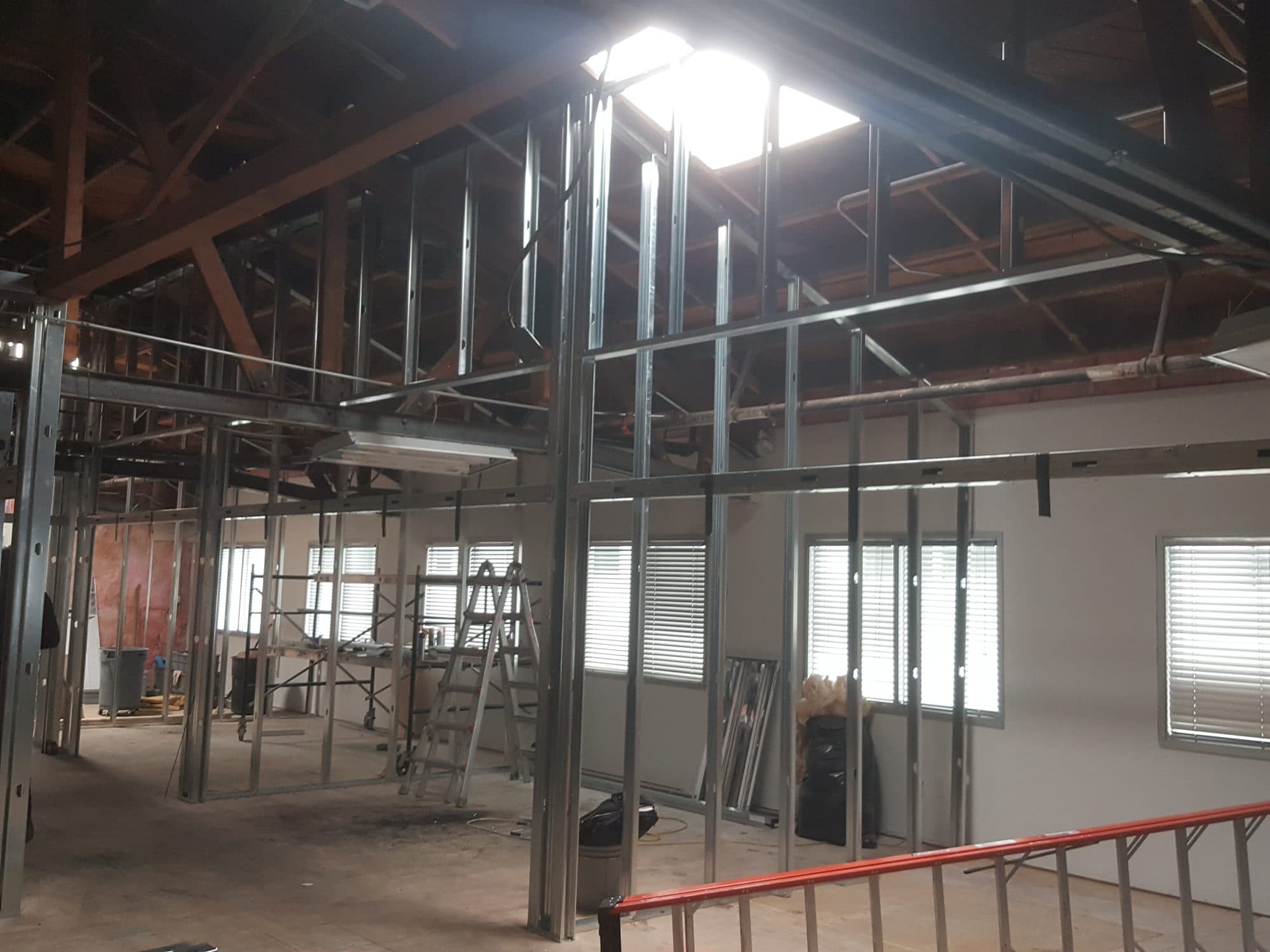 New metal-stud walls rising under a skylight in the open shell