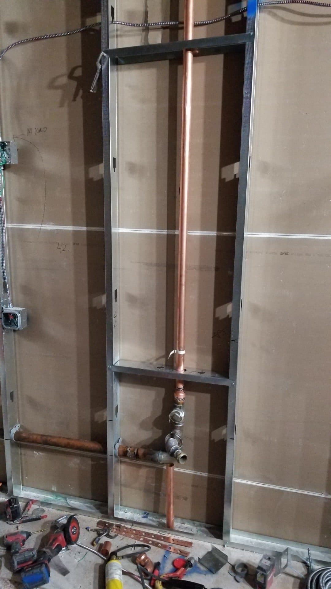 Copper supply and fixture carrier framed into a metal-stud wall