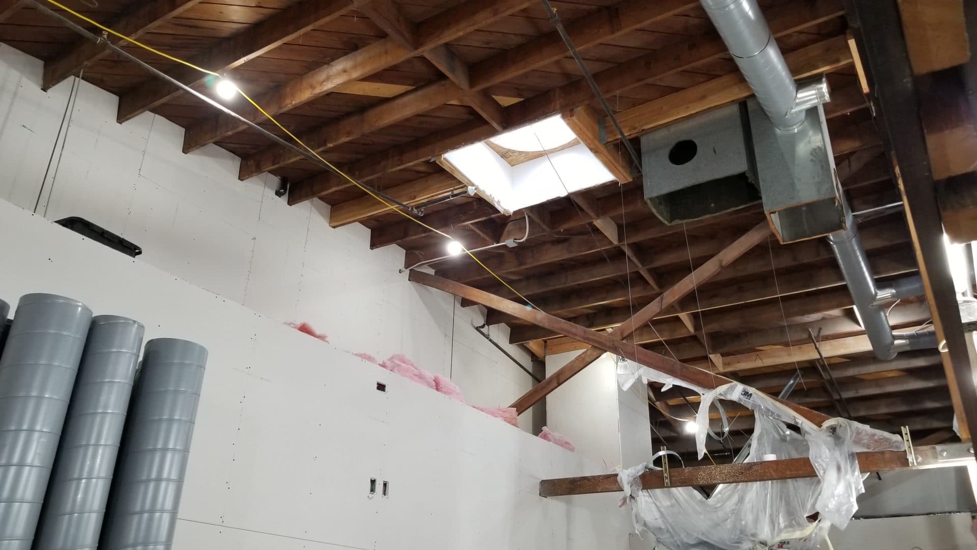 Drywall going up under the trusses with skylight, ductwork, and spiral duct staged
