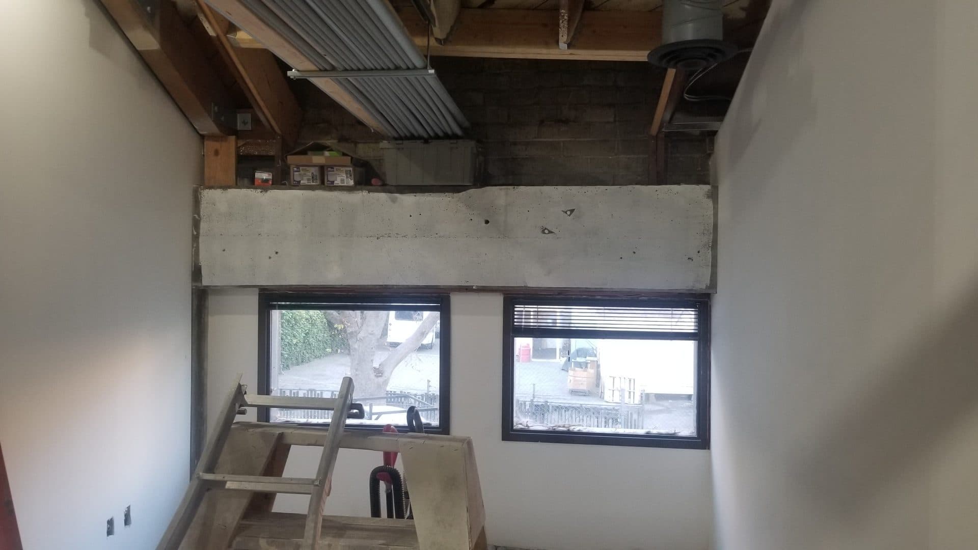 New window openings cut into the block wall with new dark-frame windows set